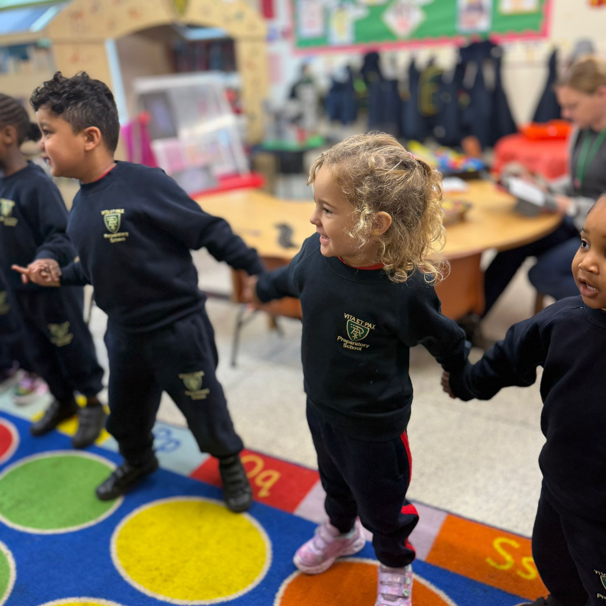 Children at Little Vita’s Nursery on a colourful rug during music and movement time